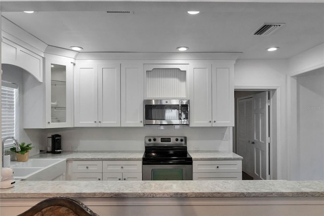 kitchen with visible vents, appliances with stainless steel finishes, glass insert cabinets, and white cabinetry