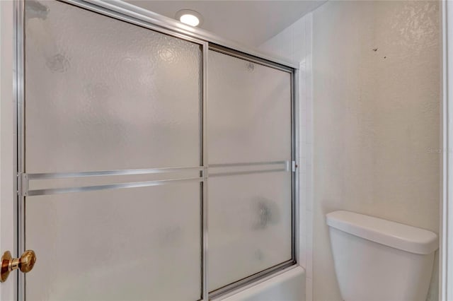 bathroom with shower / bath combination with glass door and toilet