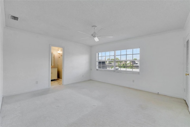 empty room with light carpet, ceiling fan, visible vents, and a textured ceiling