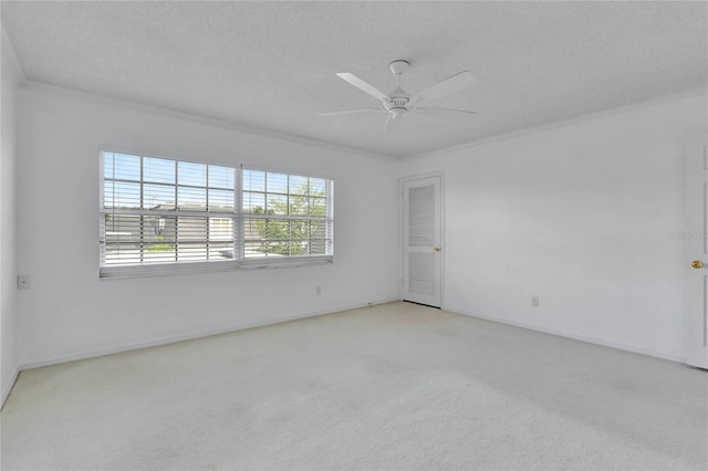 spare room with a ceiling fan, light colored carpet, plenty of natural light, and a textured ceiling