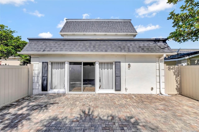 back of property featuring mansard roof, a patio, and roof with shingles