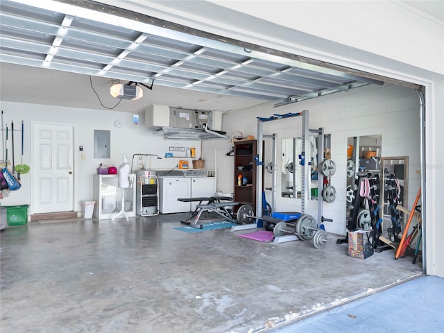 garage featuring concrete block wall, washing machine and clothes dryer, electric panel, and a garage door opener