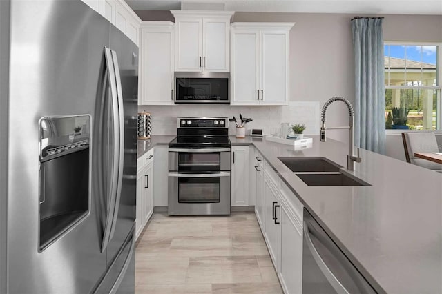 kitchen with decorative backsplash, appliances with stainless steel finishes, white cabinetry, and sink