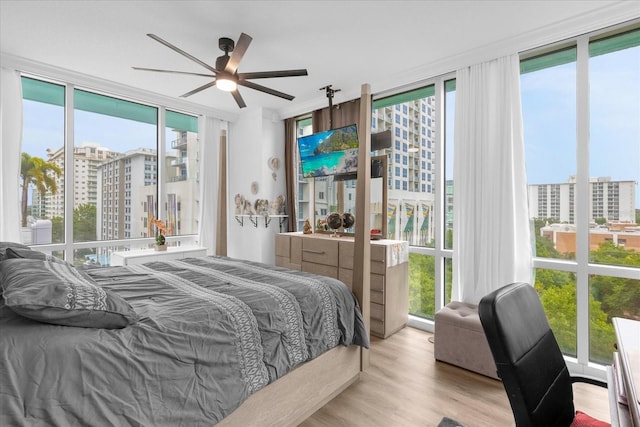 bedroom featuring ceiling fan, light hardwood / wood-style flooring, and expansive windows