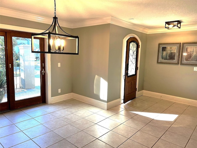 tiled entryway featuring a textured ceiling, ornamental molding, and a chandelier