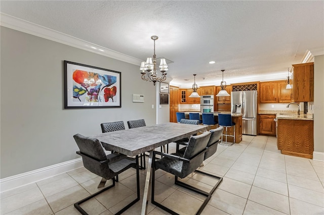 tiled dining space featuring a textured ceiling, crown molding, and sink