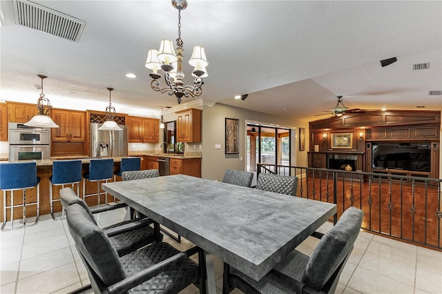 dining room with ceiling fan with notable chandelier, a textured ceiling, lofted ceiling, and light tile patterned flooring