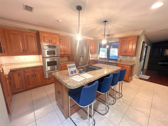 kitchen featuring a breakfast bar area, stainless steel appliances, hanging light fixtures, ornamental molding, and a center island