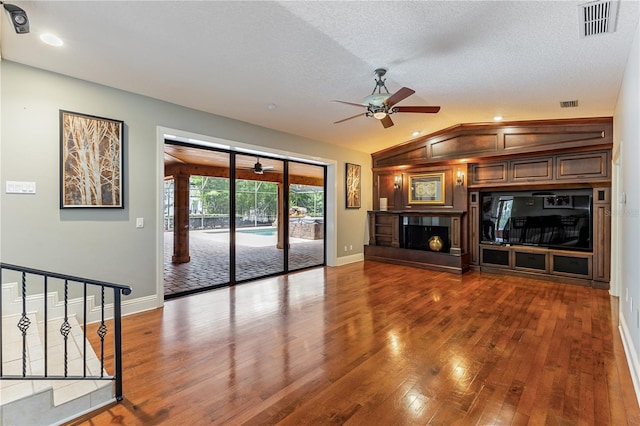 unfurnished living room with ceiling fan, a textured ceiling, wood-type flooring, and lofted ceiling