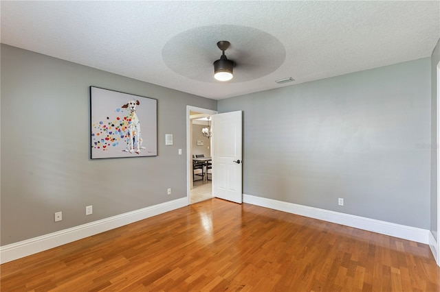 empty room with a textured ceiling, ceiling fan, and hardwood / wood-style floors