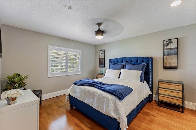 bedroom with a textured ceiling, ceiling fan, and hardwood / wood-style flooring