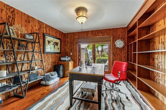 office space featuring wood walls, a textured ceiling, and hardwood / wood-style floors