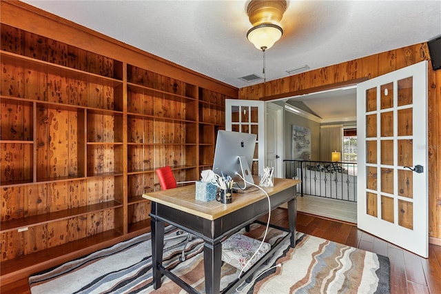 home office featuring french doors, a textured ceiling, dark hardwood / wood-style floors, and wooden walls