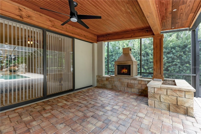 unfurnished sunroom with ceiling fan, a healthy amount of sunlight, wood ceiling, and exterior fireplace