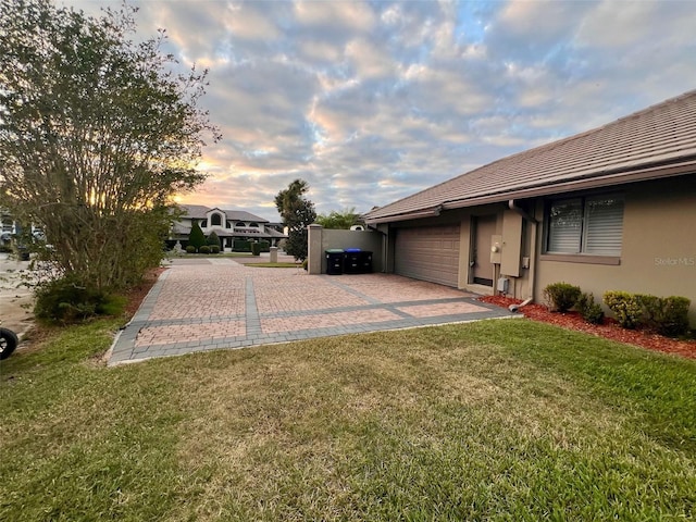 yard at dusk featuring a garage