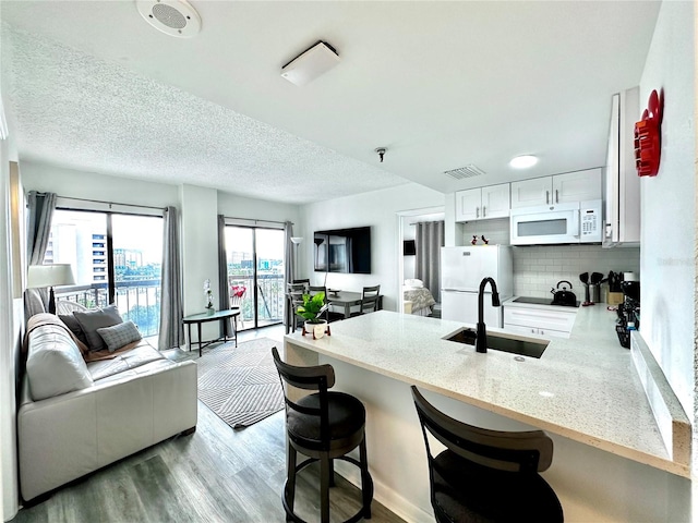 kitchen featuring tasteful backsplash, white appliances, sink, hardwood / wood-style flooring, and white cabinetry