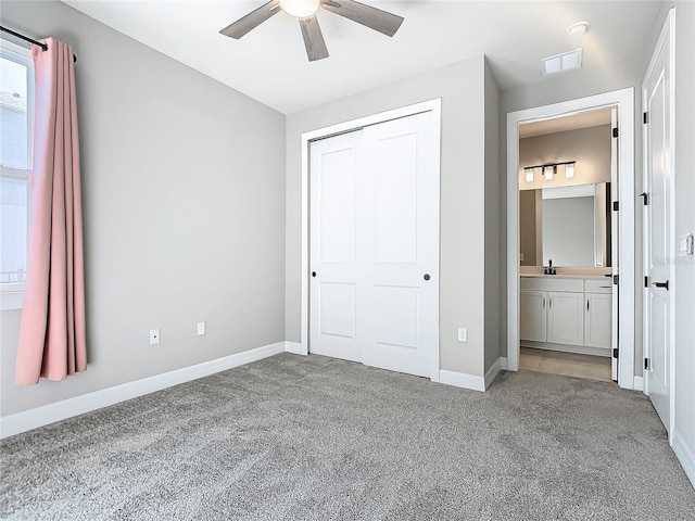 unfurnished bedroom with sink, ensuite bath, ceiling fan, light colored carpet, and a closet