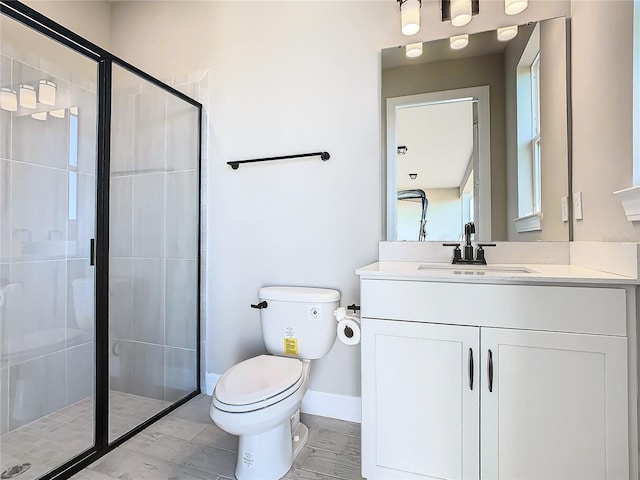 bathroom featuring a shower with door, vanity, and toilet