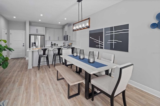 dining area with light wood-style flooring, baseboards, and recessed lighting