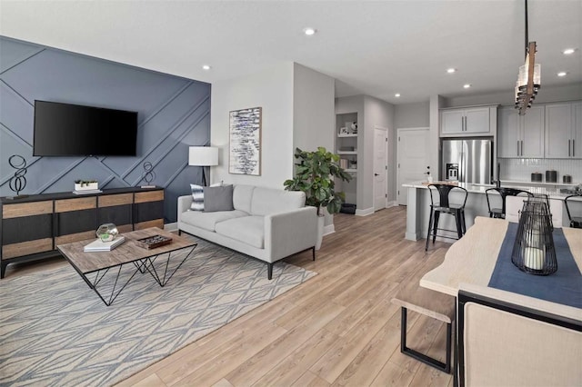 living area featuring baseboards, light wood-type flooring, and recessed lighting