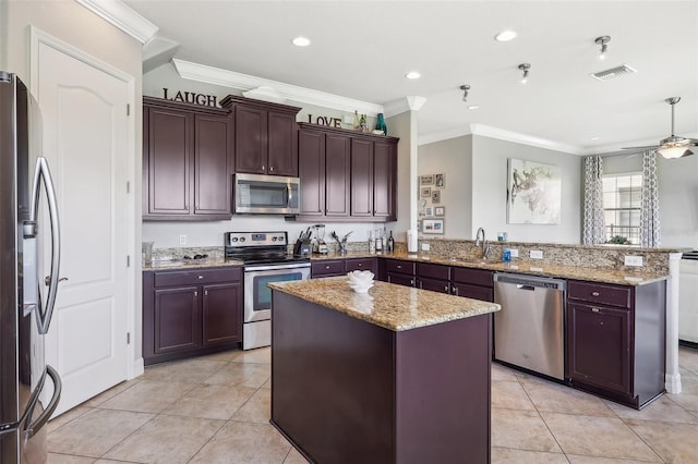 kitchen featuring light stone counters, a center island, kitchen peninsula, and appliances with stainless steel finishes