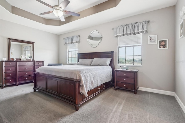 carpeted bedroom featuring a tray ceiling and ceiling fan