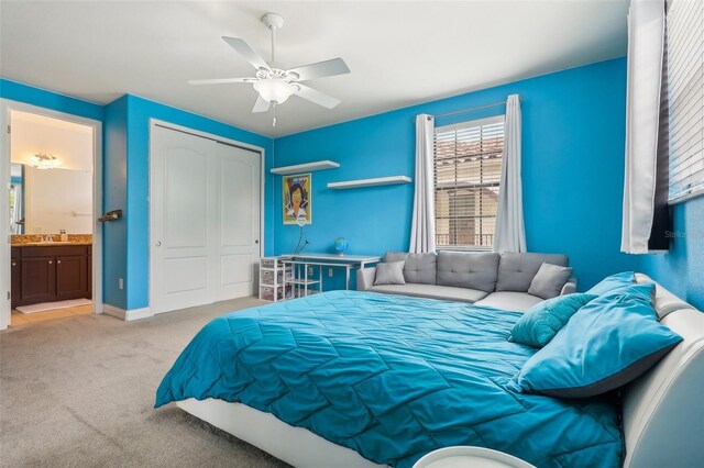 bedroom featuring ceiling fan, a closet, connected bathroom, and light carpet