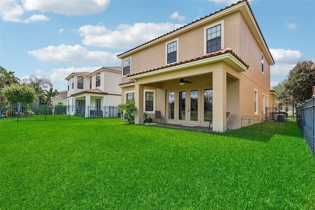 back of property with a yard, ceiling fan, and french doors