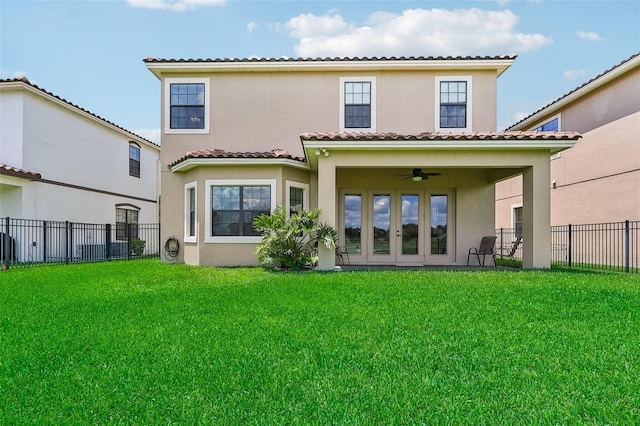 rear view of house with ceiling fan and a yard