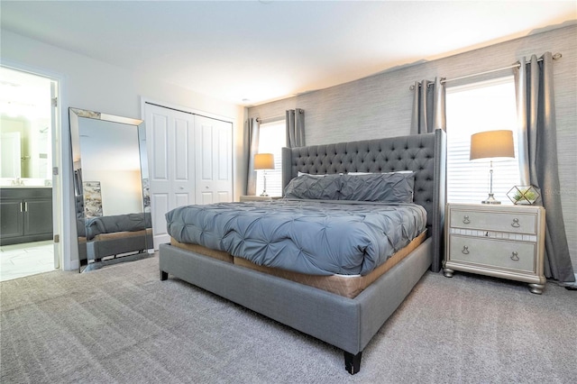 carpeted bedroom with ensuite bathroom, a closet, and sink