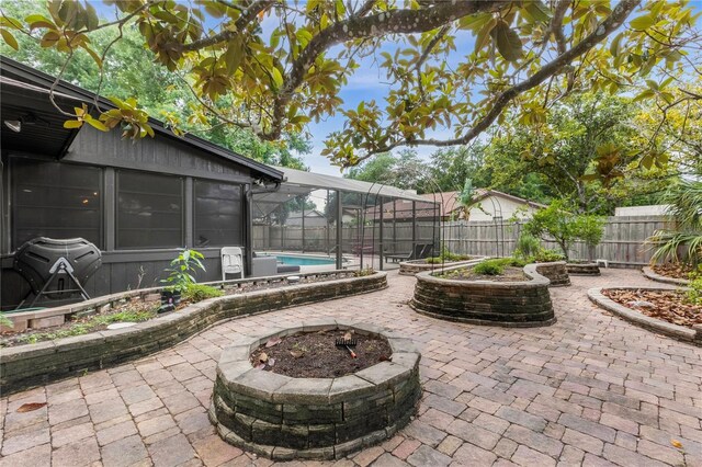 view of patio / terrace with a fenced in pool, glass enclosure, and an outdoor fire pit