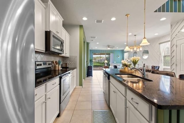 kitchen with stainless steel appliances, tasteful backsplash, an island with sink, white cabinets, and sink