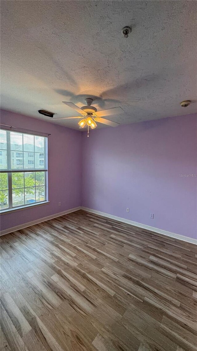 empty room with ceiling fan, a textured ceiling, and hardwood / wood-style floors