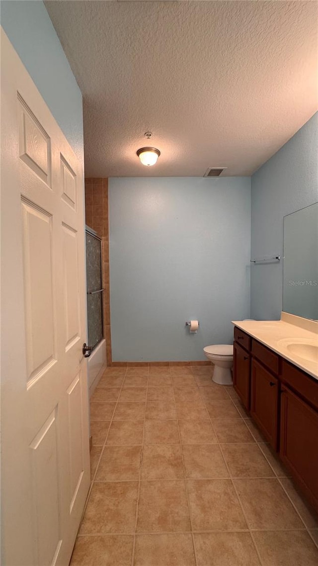 full bathroom featuring toilet, vanity, tile patterned flooring, a textured ceiling, and shower / bath combination with glass door