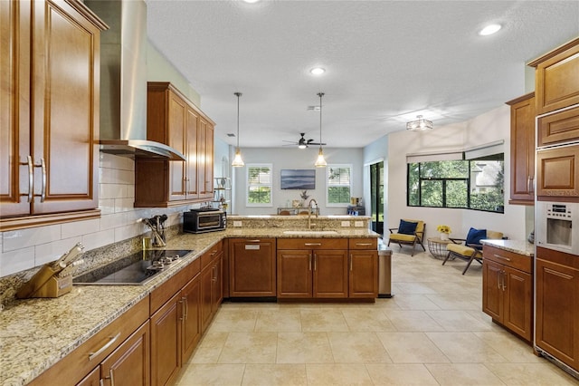 kitchen with kitchen peninsula, hanging light fixtures, sink, wall chimney exhaust hood, and black electric cooktop