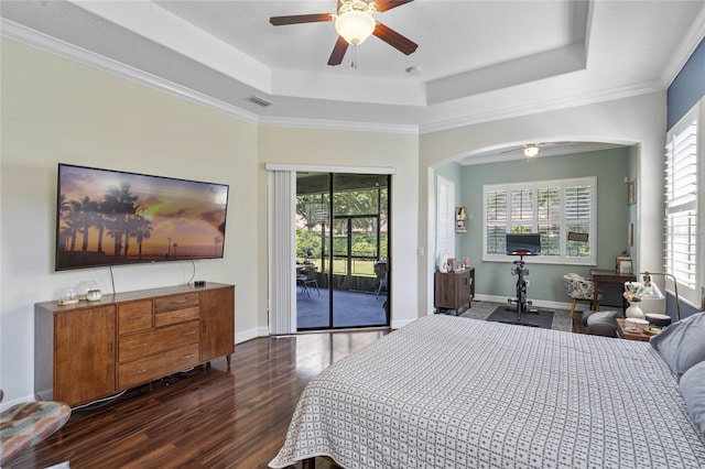 bedroom with ceiling fan, access to exterior, multiple windows, and a tray ceiling