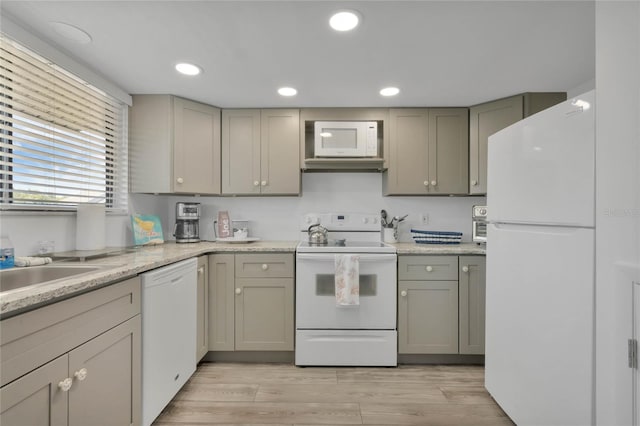 kitchen featuring light wood-type flooring, white appliances, light stone counters, and gray cabinetry