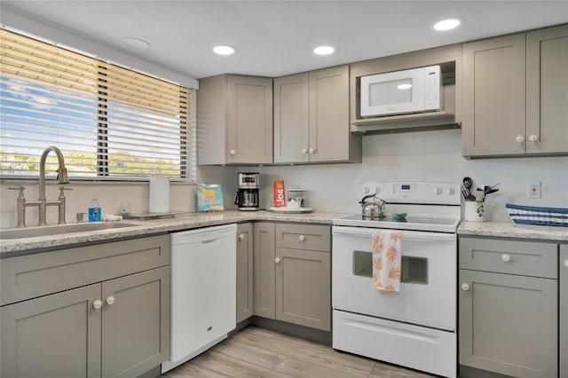 kitchen with white appliances, light hardwood / wood-style floors, gray cabinetry, and sink