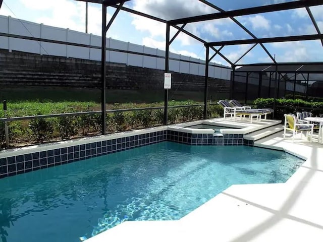 view of pool featuring glass enclosure, a patio area, and a pool with connected hot tub