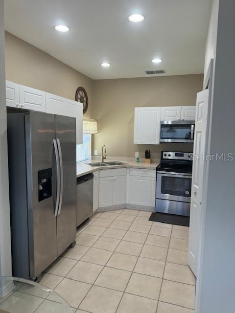 kitchen featuring light tile patterned floors, appliances with stainless steel finishes, sink, and white cabinetry