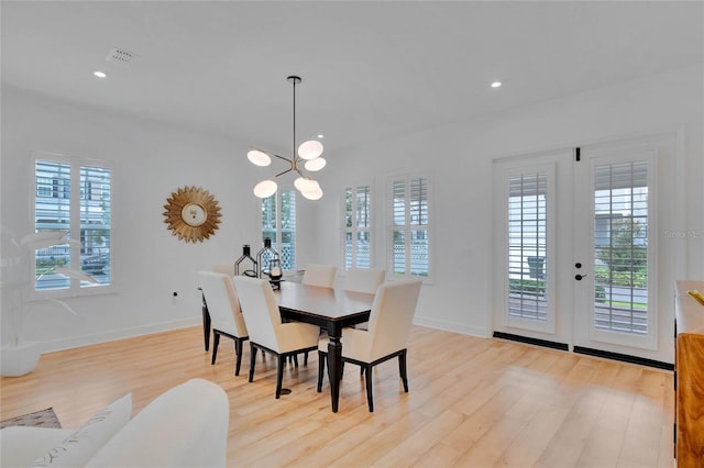 dining space with a healthy amount of sunlight, light wood-type flooring, and a chandelier