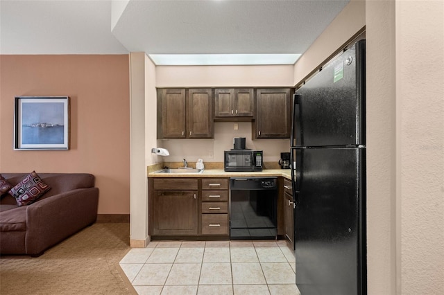 kitchen with dark brown cabinetry, black appliances, sink, and light tile floors