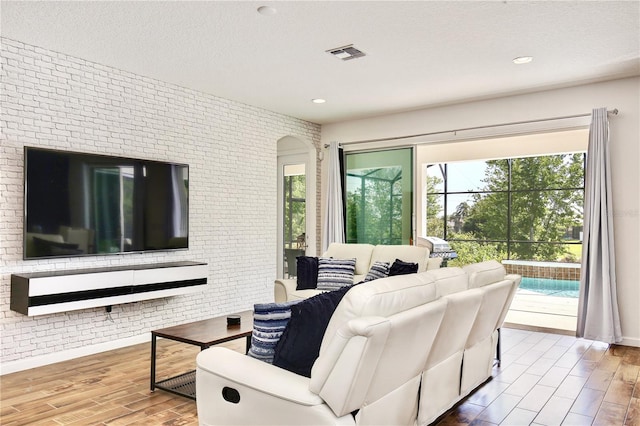 living room with a textured ceiling, a healthy amount of sunlight, and brick wall