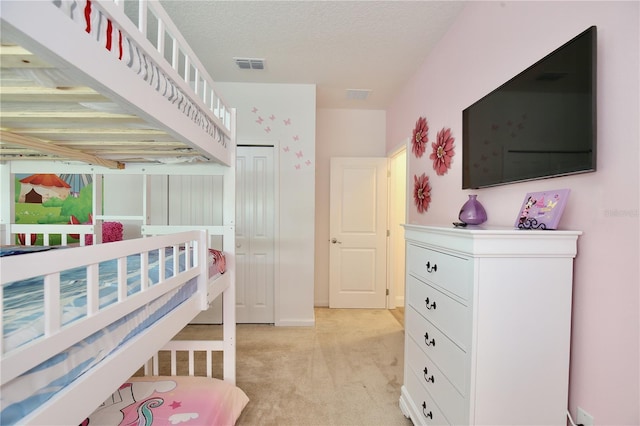 carpeted bedroom with a textured ceiling and a closet