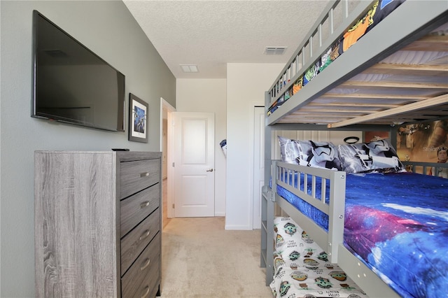 bedroom with light colored carpet and a textured ceiling