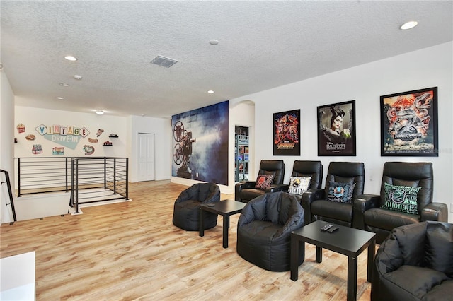 home theater room with light hardwood / wood-style floors and a textured ceiling