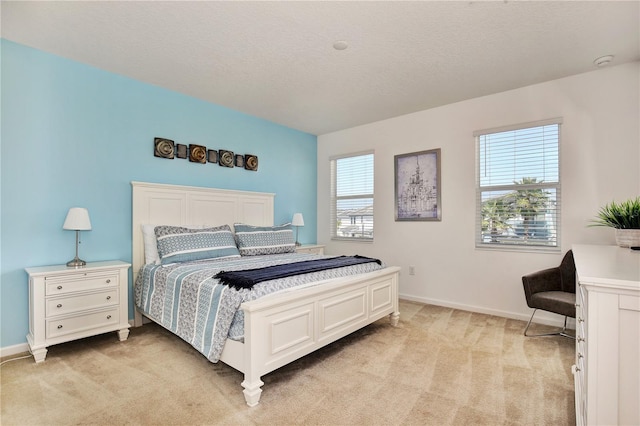 bedroom with light colored carpet and a textured ceiling