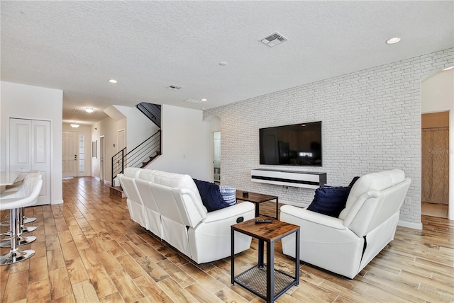 living room featuring a textured ceiling and brick wall