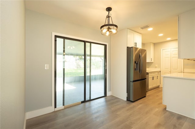 4230 Ponds Dr, Cocoa, FL 32927 - kitchen with stainless steel refrigerator with ice dispenser, white cabinets, light countertops, light wood finished floors, and recessed lighting