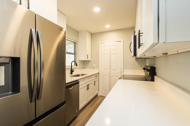 4230 Ponds Dr, Cocoa, FL 32927 - kitchen featuring appliances with stainless steel finishes, a sink, white cabinets, dark wood-style flooring, and light countertops